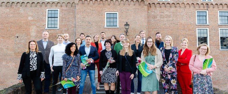 Op de foto (vlnr): Patricia Geerts, Jacob Meesters, Tim Koning, Michiel Flipsen, Els Roetman, Katya Kuznetsova, Christiaan van Dam, Boy Hoogeveen, Denise van Dijk, Arjen de Booij, Dianne Derksen, Hanin Alsa’ati, Marc Buts, Lotte Bruijnen, Marit Hooijberg, Hans Duijn, Berthilde Spreij, Dirk Schut, Annelore Schilstra, Wilma Venmans (voorzitter Centrale Examencommissie) en Dieuwke Dillo.  